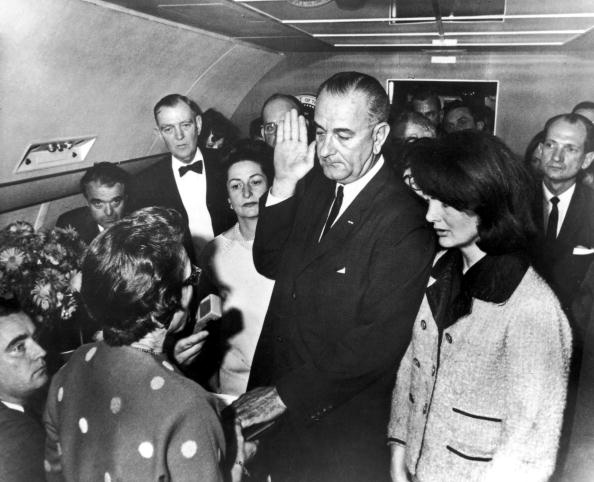 UNITED STATES - NOVEMBER 22:  VP Lyndon Johnson (C) taking oath of office from Judge Sarah Hughes (back to camera) after President Kennedy's assassination aboard Air Force One. Former First Lady Jackie Kennedy (R), imminent First Lady Lady Bird (L), Jack Valenti, Congressmen Albert Thomas  (Photo by Cecil Stoughton/The LIFE Images Collection/Getty Images)